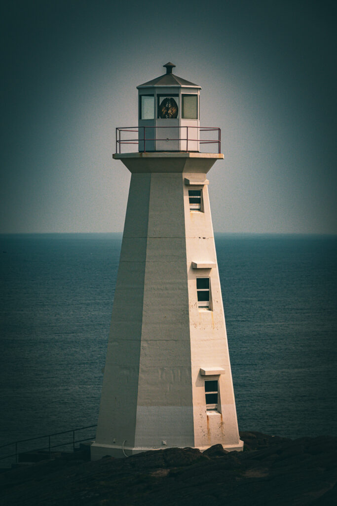 Cape Spear Lighthouse stands tall in the centre of the image, with a blue horizon behind it and a dark vignette around the corners of the photos.